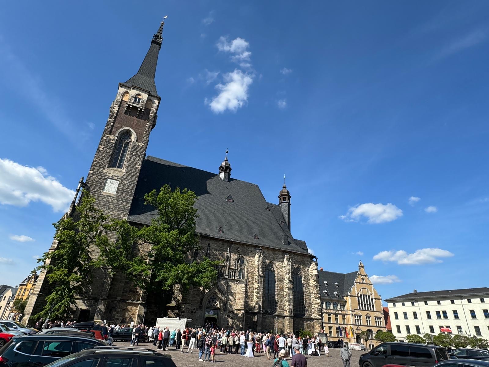 Die Stadtkirche St. Jakob mit vielen Menschen davor und bei strahlend blauem Himmel