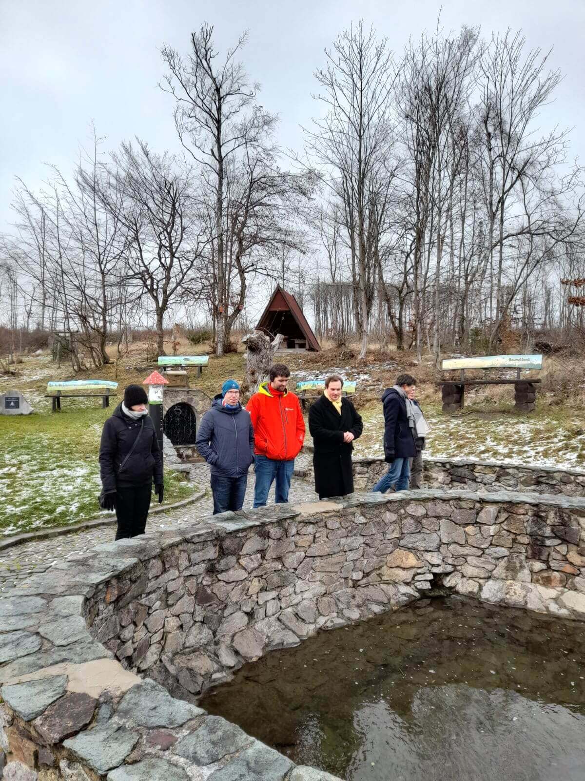 5 Menschen vor einem Brunnen mit Feldstein gemauerter Umrandung