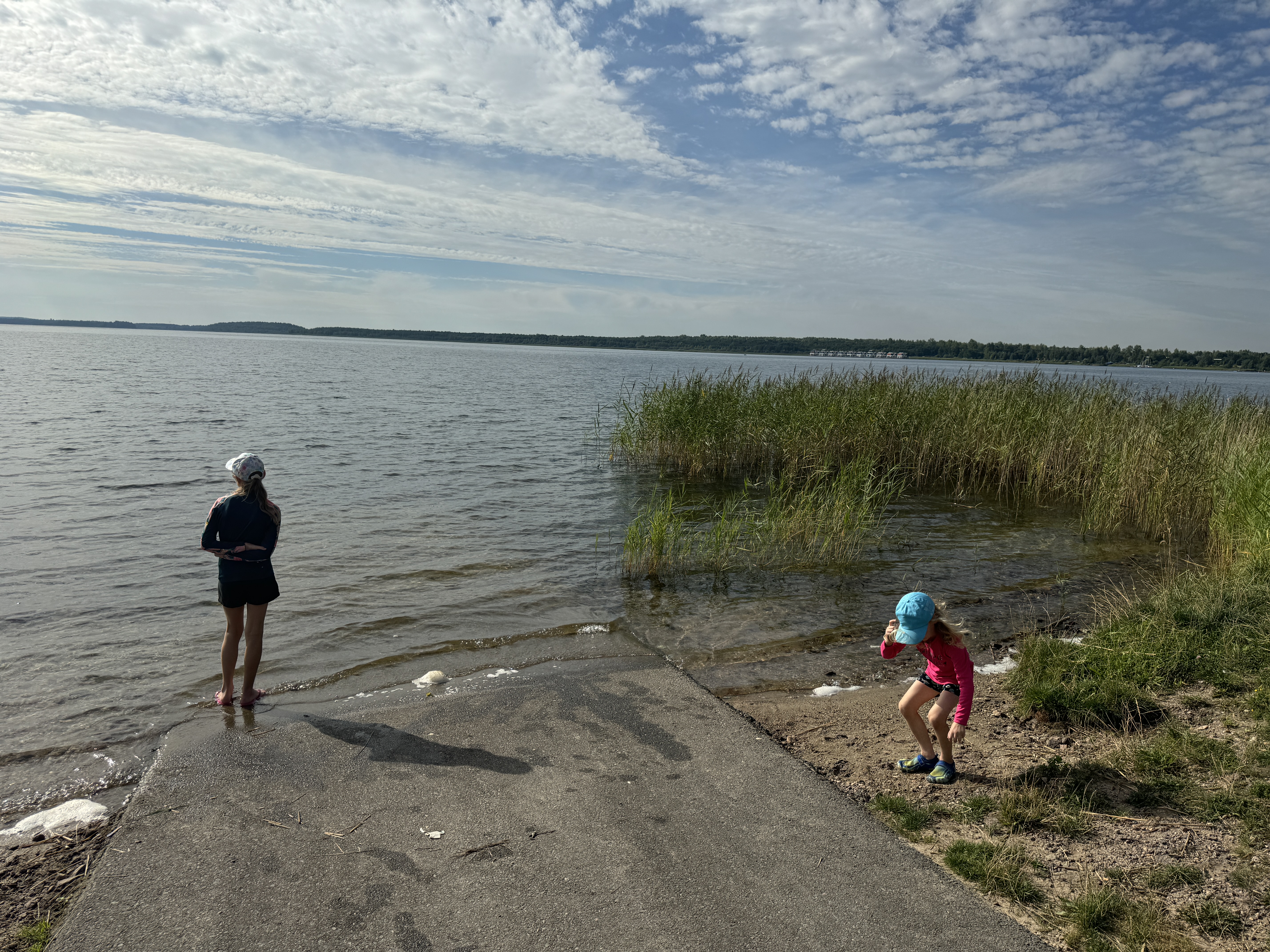 zwei Kinder stehen an einem See bei Sonnenschein